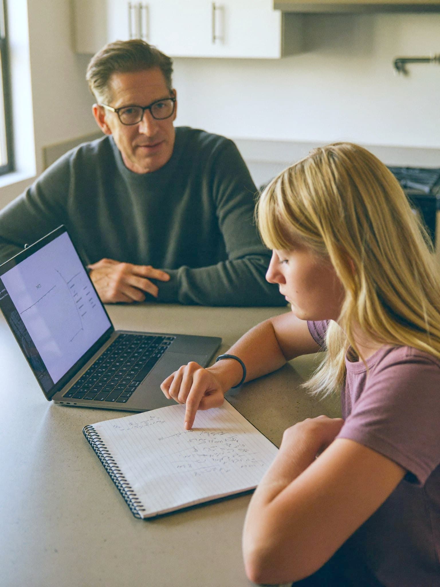 A teacher listening while a teenager points at her own working