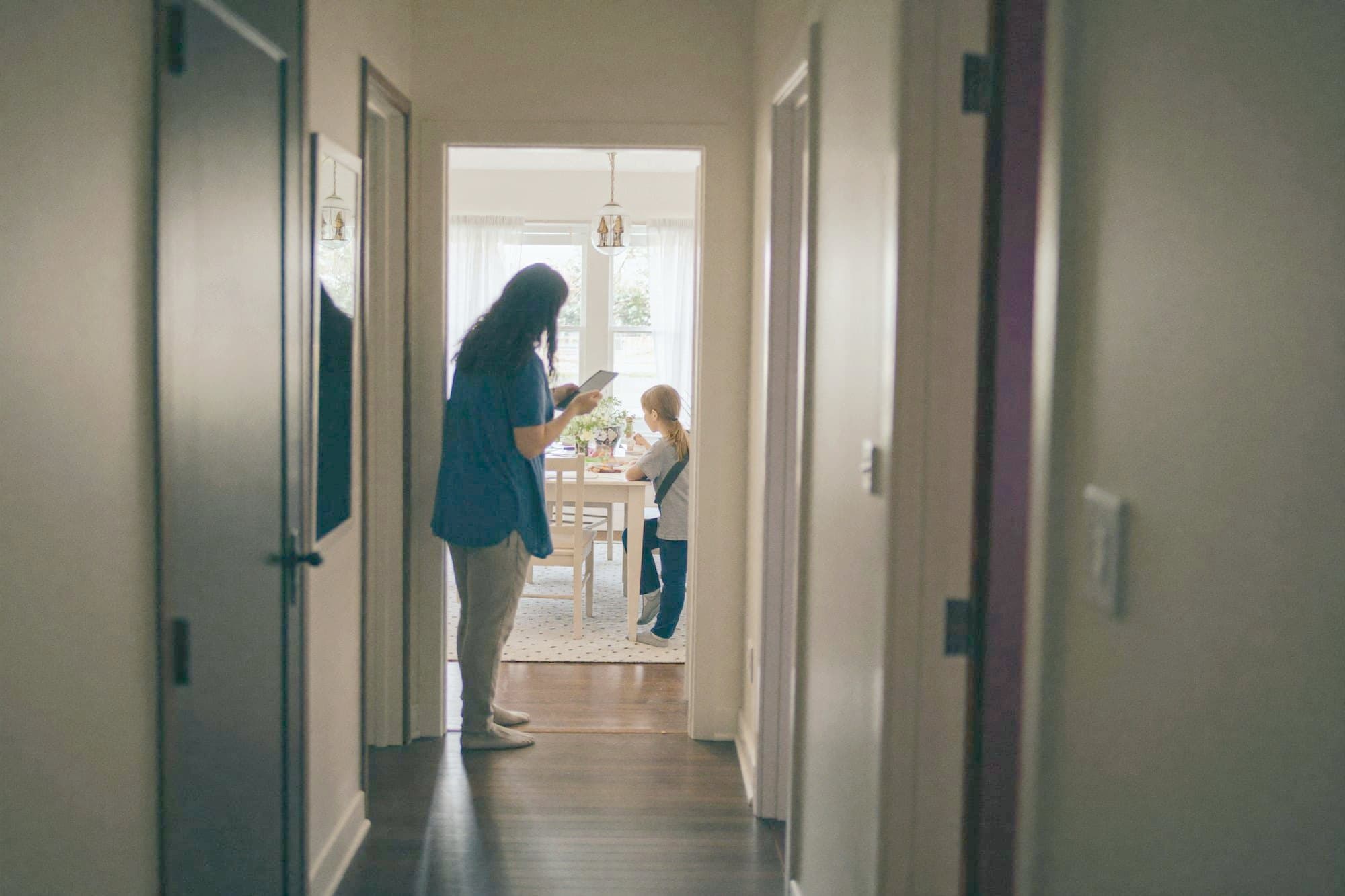 A parent watching from the doorway while a lesson goes on at the table