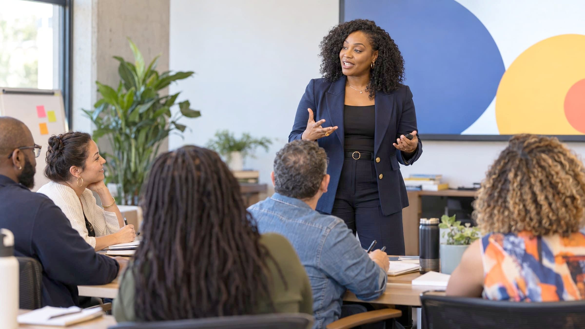 A presenter speaking to a room of adults taking part in a session.